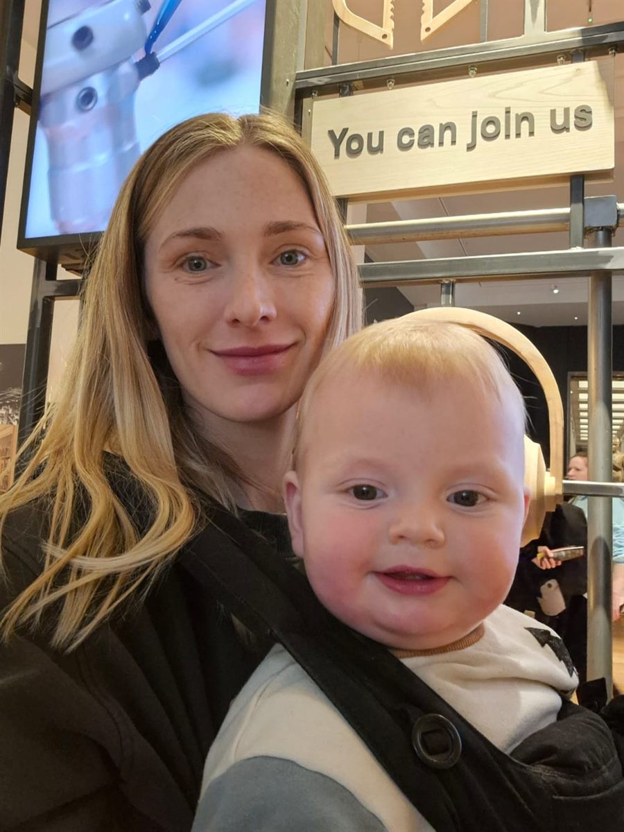 Jacqueline smiling, with her baby in a sling carrier